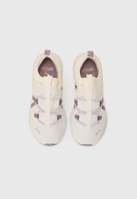 Light cream athletic shoes with a textured upper, elastic straps, and purple accent details. Features a pull tab at the heel for easy wear.