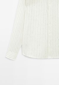 White long-sleeve button-up shirt with thin black vertical stripes and a cuffed sleeve on a plain white background.