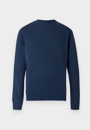 Tmavomodrá mikina s okrúhlym výstrihom, žíhanými manžetami a lemom. Na hrudi je jemné logo v rovnakej farbe. Hladká textúra látky.