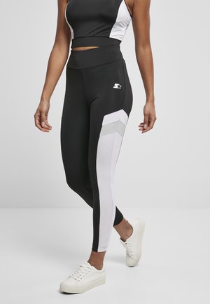 Black and white athletic leggings with a high waistband, featuring a diagonal white panel and reflective accents on the side.