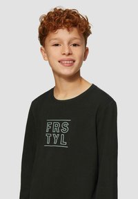 Zwarte lange mouwen shirt van katoen, met op de voorkant een lichte blauwe grafische tekst "FRSTYL". Rond halslijn met een soepele textuur.