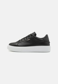 Zapatilla negra de cuero con superficie texturizada, suela blanca en contraste, diseño de cordones y pequeño detalle metálico en el lado.