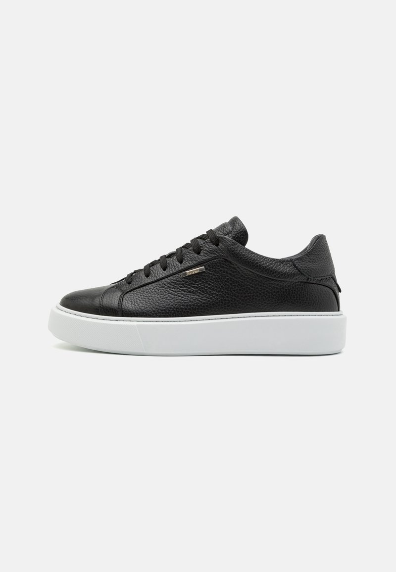 Zapatilla negra de cuero con superficie texturizada, suela blanca en contraste, diseño de cordones y pequeño detalle metálico en el lado.