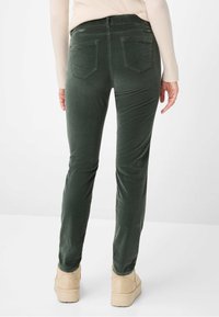 Mørkegrønne manchesterbukser med en slank pasform, der har to baglommer og en glat tekstur. Båret med lysebrune platformsko.