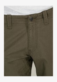 Olive green pants with a smooth texture, featuring horizontal ribbed pattern, a metal button closure, and belt loops.