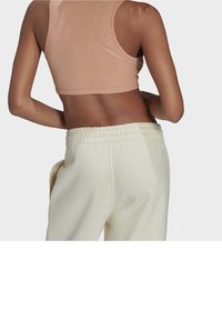 Jasnoróżowy, prążkowany cropped top w połączeniu z kremowymi, luźno dopasowanymi spodniami dresowymi z elastycznym paskiem i bocznymi kieszeniami.