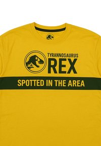 Gelbes Baumwoll-T-Shirt mit einem schwarzen Tyrannosaurus rex-Graphic, "Tyrannosaurus REX" und "SPOTTED IN THE AREA" in grüner Schrift.