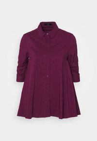 Camicia viola con bottone, colletto, dettagli arricciati sulle maniche e una siluotette svasata. Tessuto dalla consistenza liscia.