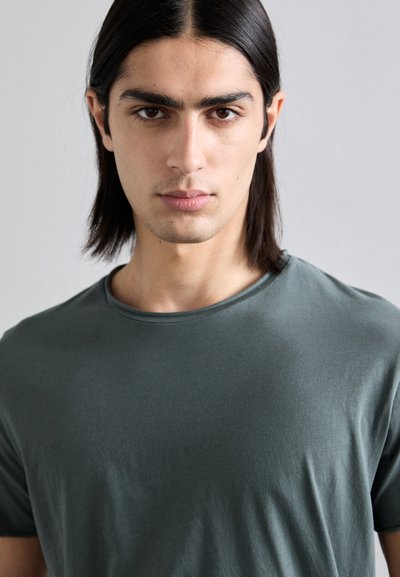 Dark green short-sleeve t-shirt with a round neck, made of smooth fabric, featuring a relaxed fit and minimal stitching details.
