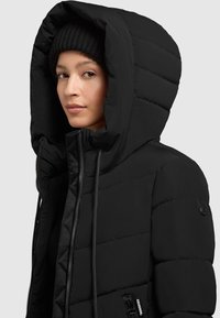 Giacca a vento nera con un grande cappuccio, design trapuntato e zip frontale. Presenta una tasca laterale e un berretto in maglia nera.