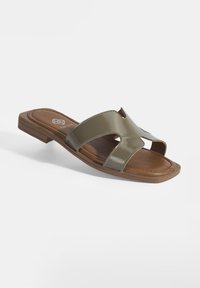 Sandales à glissière vert olive avec une finition glossy, bout ouvert, deux larges sangles et une semelle texturée marron. Design à petit talon carré.