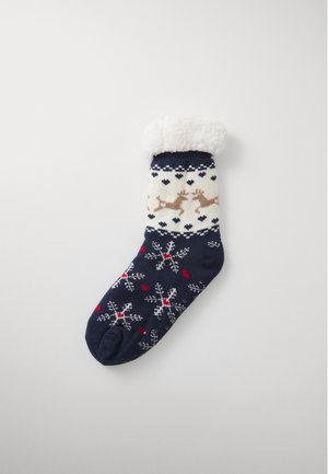 Calcetín azul marino con un puño crema, que presenta patrones de renos y copos de nieve en beige, rojo y blanco. Textura suave con una parte superior de felpa.