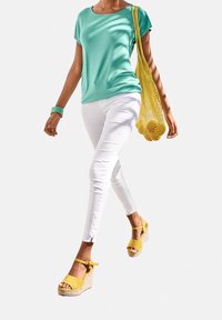 Turkoosi lyhythihainen paita, valkoiset kapeat farkut rikotuilla helmilla, keltaiset korkeat sandaalit ja keltainen verkoselkäinen käsilaukku.