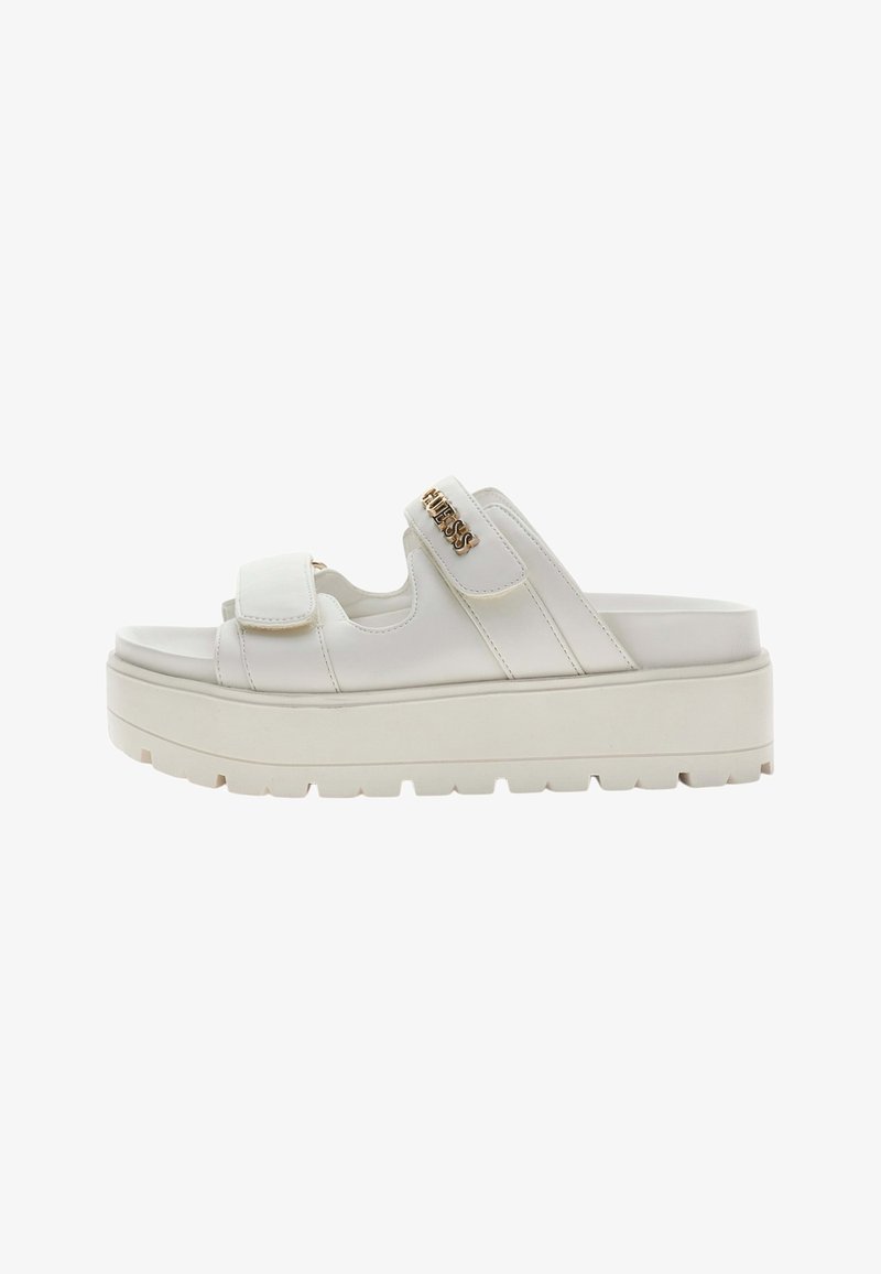White platform sandal with two adjustable straps, chunky sole, and gold "GUESS" logo on the upper strap.