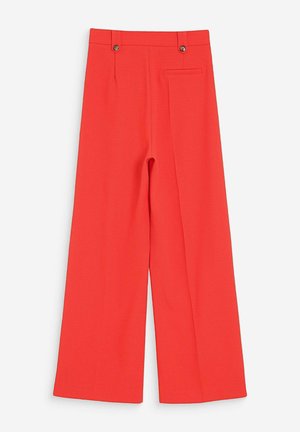 Pantalon rouge à jambes larges, taille haute, avec deux boutons sur la ceinture et une poche latérale unique, sur fond blanc.