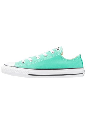 Lysegrøn lærredsneaker med lavt snit, hvid gummisål og tre øjer. Har en sort stribe langs sålen og textured tåhætte.