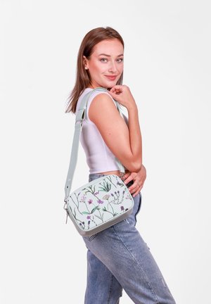 Umhängetasche mit floralem Muster in hellem Mintgrün, mit Reißverschluss und verstellbarem Trageriemen, ausgestattet mit botanischen Illustrationen in Rosa und Lila.
