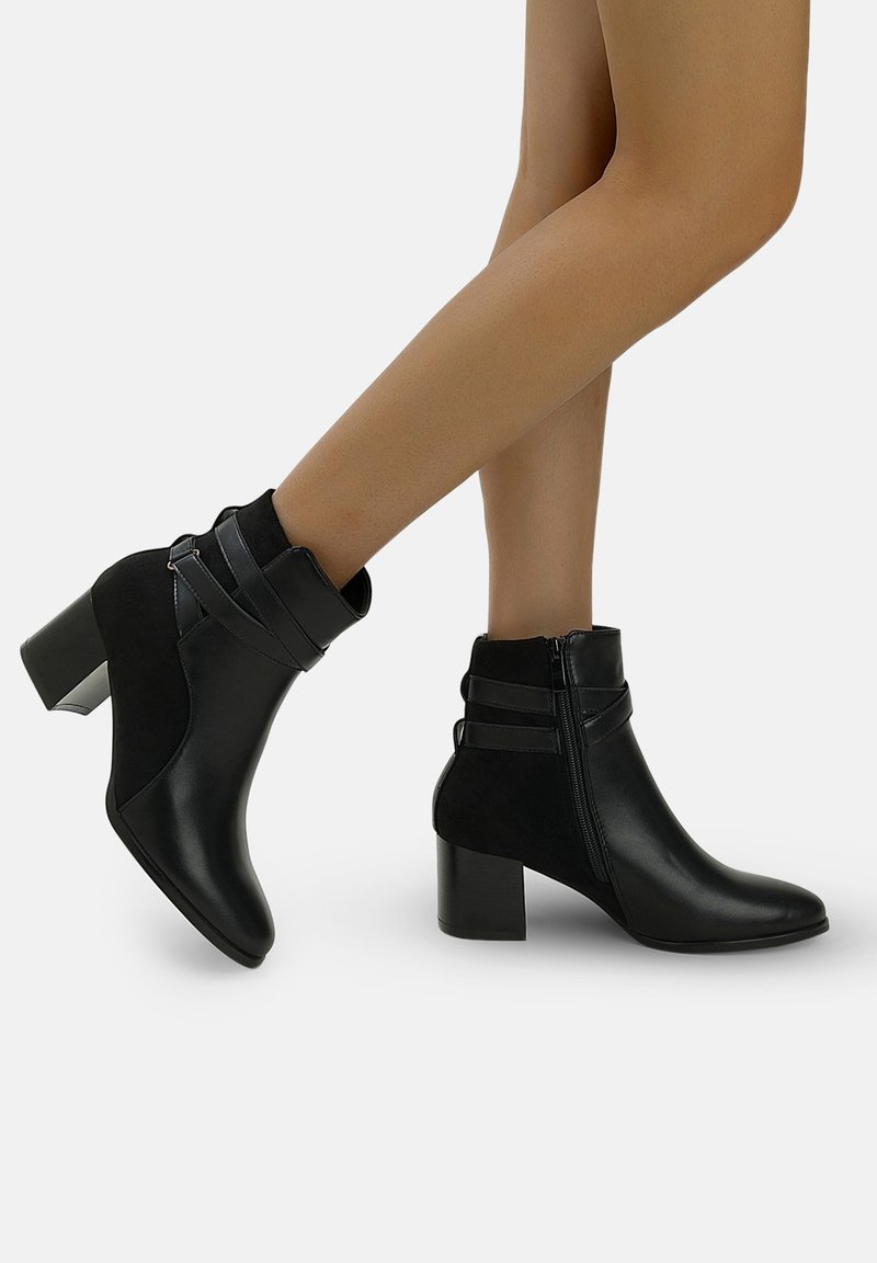 Stivaletti neri che presentano una combinazione di pelle liscia e suede morbido, con un tacco spesso e accenti decorativi con cinturini.