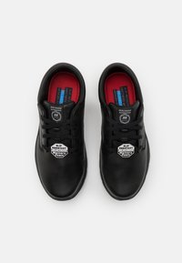 Chaussures en cuir noir à bout rond, dotées d'un design antidérapant, d'une fermeture à lacets et de semelles intérieures rouges rembourrées. Intérieur en mousse à mémoire de forme.