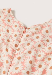 Tela de blusa floral rosa con margaritas blancas y centros marrones, textura suave, escote redondeado y detalle de cremallera en la parte posterior.
