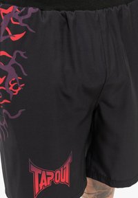 Sorte atletiske shorts med et lilla og rødt grafisk design på den ene side og et rødt "TAPOUT" logo på den nedre front. Glat, letvægtsstof.