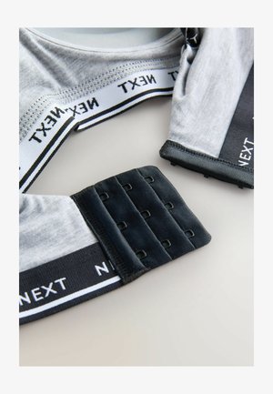 Šedá tkanina s černou a bílou elastickou páskou s nápisem "NEXT". Viditelný nastavovací černý háček a očko. Měkká textura.