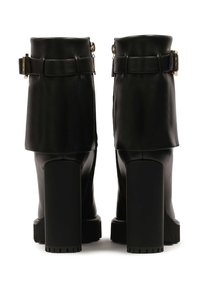 Bottines en cuir noir avec un revers plié, une fermeture éclair latérale et de grands talons épais. Agrémentées d'une boucle dorée sur chaque revers.