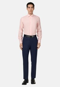 Jasnoróżowa, w paski koszula z długim rękawem i zapięciem na guziki, zestawiona z ciemnogranatowymi spodniami oraz czarnym paskiem, noszona z czarnymi butami.