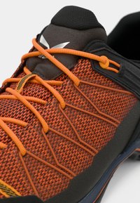 Oranje textuur hardloopschoen met oranje veters, zwarte accenten en een gevoerde tong. Synthetisch materiaal met een duurzaam zoolontwerp.