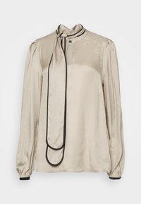 Blusa di satin beige chiaro con colletto alto e rifiniture nere. Presenta maniche lunghe, una chiusura frontale con bottoni e un fiocco decorativo al colletto.