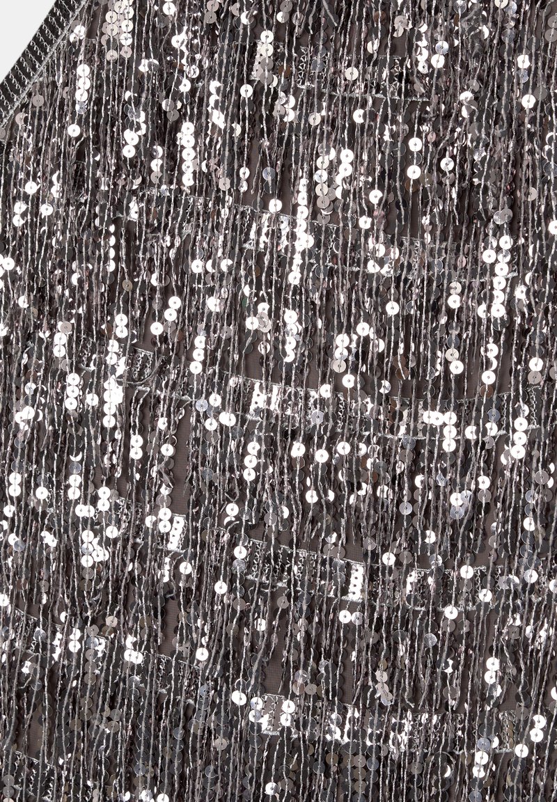 Srebrny materiał z cekinami z pionowym wykończeniem frędzlami. Odbijające się okręgi tworzą fakturowaną, lśniącą powierzchnię, idealną do odzieży lub dekoracji.