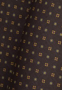 Brązowy materiał z powtarzającym się wzorem małych kwiatków w kolorze żółtym, niebieskim i fioletowym. Tekstura wydaje się gładka z delikatnym prążkowaniem.