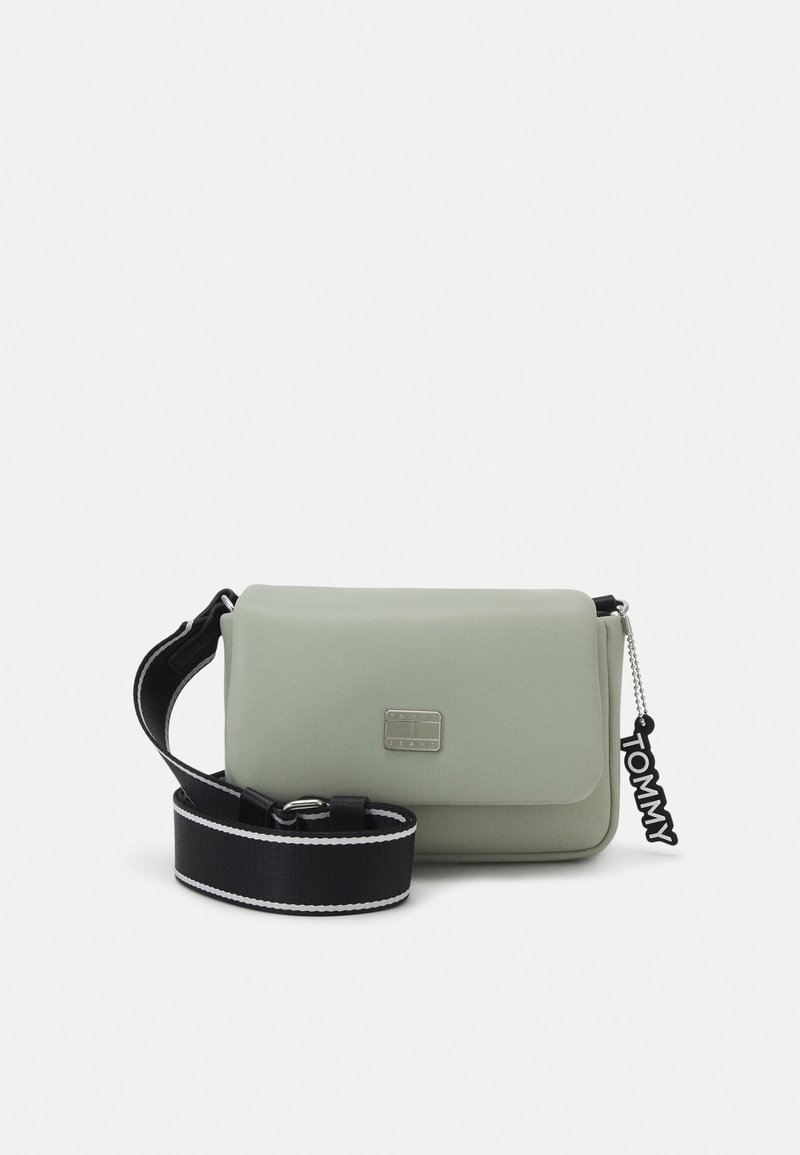 Borsa a tracolla verde in ecopelle con tracolla nera, hardware argentato, chiusura a pattina e un charm nero "TOMMY" attaccato.