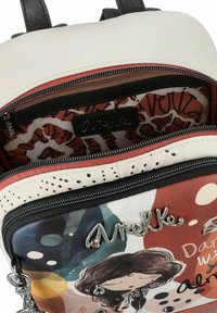 Sac à dos coloré alliant cuir et tissu. Zips noirs remarquables, imprimés artistiques en rouge, bleu et crème, avec des accents en argent.