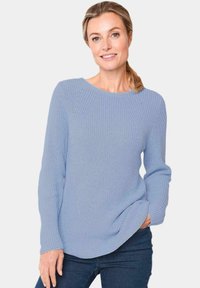 Helles blaufarbenes Strickpullover mit Rundhalsausschnitt, strukturiertem Stoff, langen Ärmeln und leicht abgerundetem Saum. Kombiniert mit dunklen Jeans.