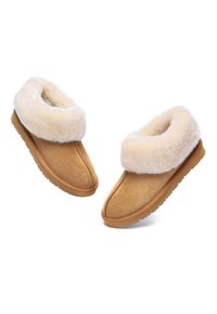 Tan suede slippers with a soft, cream-colored shearling cuff. Rounded toe, textured sole for grip, and visible stitching details.