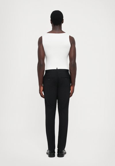Weißes ärmelloses Oberteil kombiniert mit schwarzen Hosen, die eine taillierte Silhouette und gerade Beine haben, mit dezenten Taschen und einem klaren Finish.