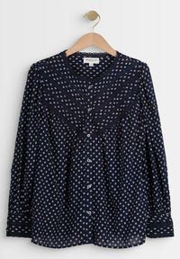 Blouse bleu marine avec motifs carrés beige clair, fermeture à boutons, manches longues et détail texturé sur le yoke. Tissu doux et léger.