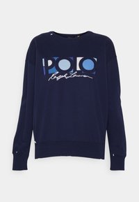Marint blå sweatshirt i bomull, med en stor "POLO"-logga i blått och vitt samt en cursive "Ralph Lauren" under. Löst snitt, ribbade manschetter.