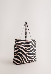 Geantă tote din pânză cu model dungi de zebră în culorile negru și nisip. Două mâneruri rezistente pentru transport. Textură moale.
