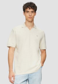Beige polo shirt met korte mouwen en een V-hals, voorzien van een klein logo aan de linkerkant. Gemaakt van zachte, gestructureerde stof.