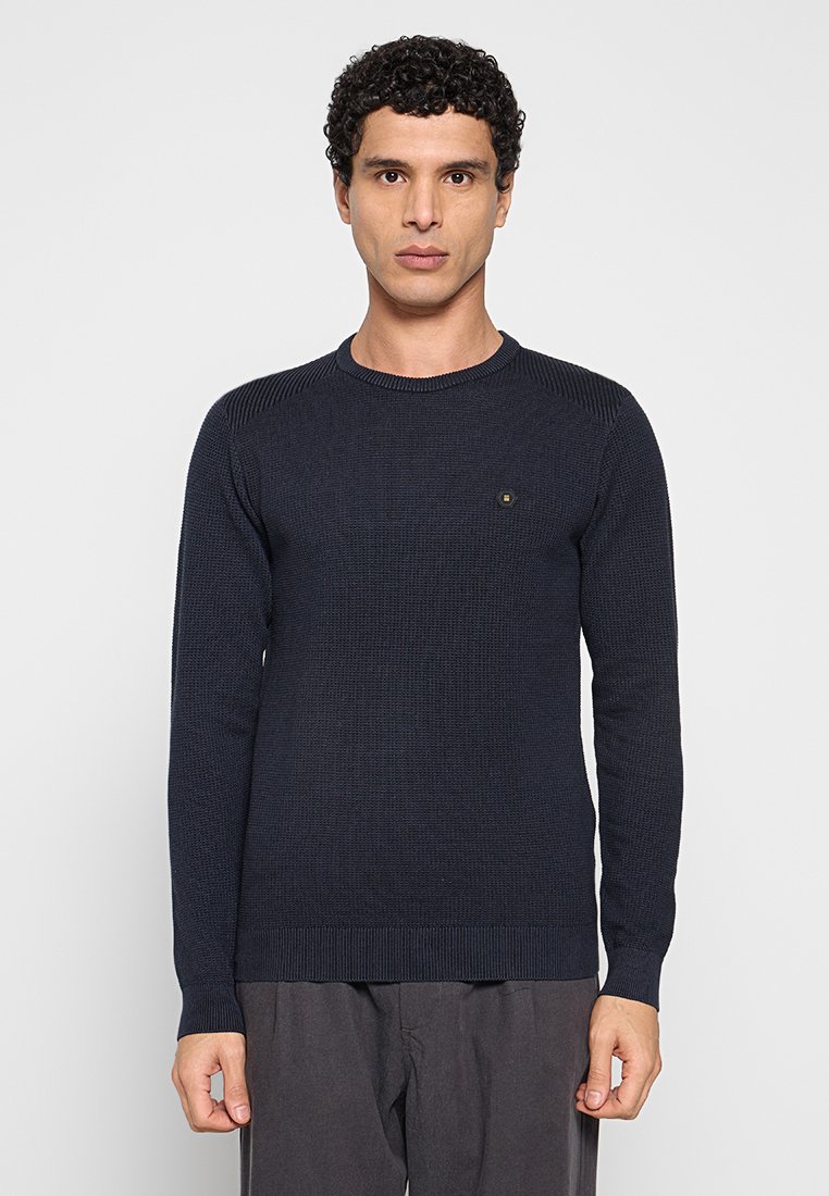 Marineblauwe gebreide trui met ronde hals, gestructureerd patroon en geribbelde manchetten en zoom. Voorzien van een klein logo op de borst.