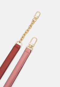 Dvě odnímatelné popruhy v burgundské a růžové kůži. Obsahují zlatý kovový řetěz a spony se silným kováním. Hladký povrch.
