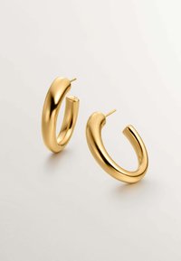 Pendientes de aro en tono dorado con un acabado suave y brillante. Cada pendiente tiene una forma curvada y redondeada con un cierre de tipo post.