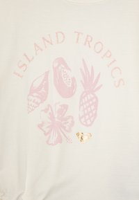 Valge t-särk, millel on glitternaha roosa graafika, kus on troopilised elemendid: merikarp, avokaado, ananass, hibiskusõis ja väike kuldne süda.