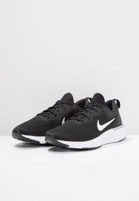 Černé sportovní boty s texturovaným svrškem, bílým logem swoosh a gumovou podešví. Obsahují kulaté tkaničky a polstrovaný límec.