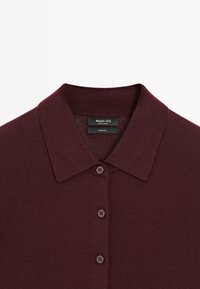 Bordeaux wollen polo shirt met een platte kraag, vier knopen en een gestructureerde brei. Het label leest "Massimo Dutti, 100% wol."