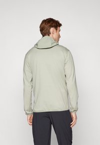 Giacca verde chiaro con cappuccio e maniche lunghe, realizzata in materiale liscio e elasticizzato, con polsini e orlo elastico.