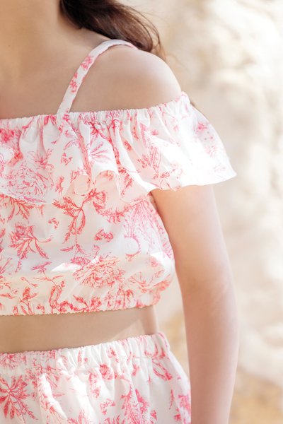 Top cropped floral e parte inferior combinando, tecido leve em branco com padrão floral rosa, design com babados, elástico na cintura e alças finas.