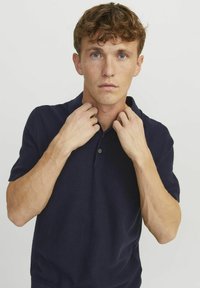 Polo shirt navy con maniche corte, tessuto strutturato e colletto classico. Caratterizzato da due bottoni al collo e vestibilità su misura.